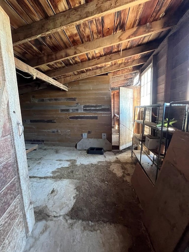 interior space featuring beamed ceiling, wood walls, and wooden ceiling