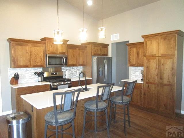 kitchen featuring brown cabinetry, stainless steel appliances, light countertops, visible vents, and high vaulted ceiling