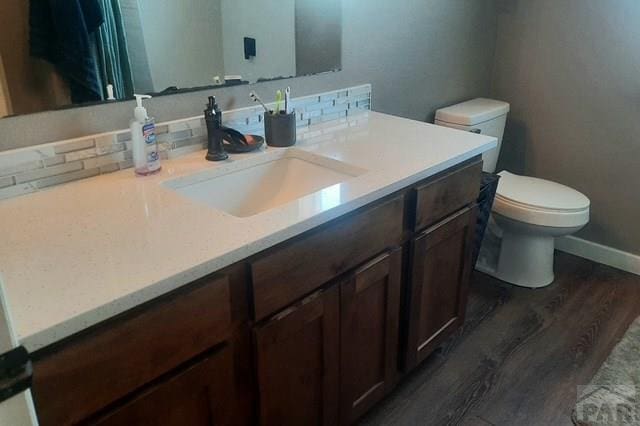 bathroom featuring wood finished floors, toilet, vanity, and baseboards