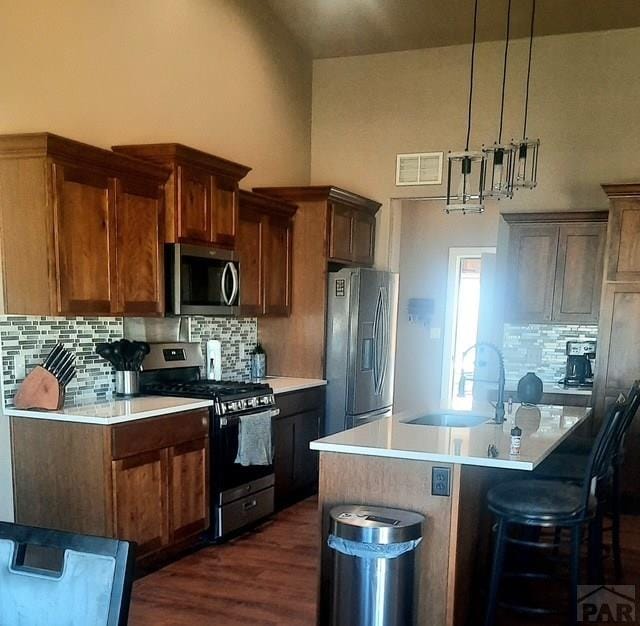 kitchen featuring a sink, stainless steel appliances, tasteful backsplash, visible vents, and light countertops