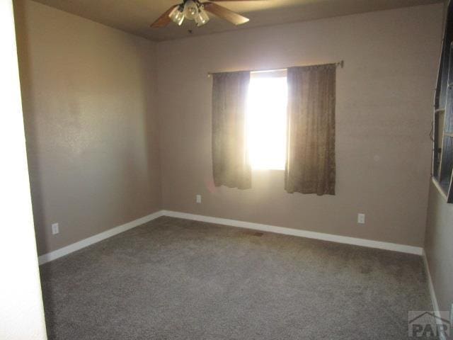 spare room featuring baseboards, ceiling fan, and carpet