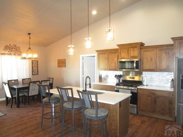 kitchen with tasteful backsplash, a breakfast bar, appliances with stainless steel finishes, brown cabinets, and a sink