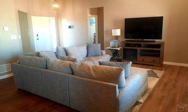 living area featuring baseboards, visible vents, and wood finished floors