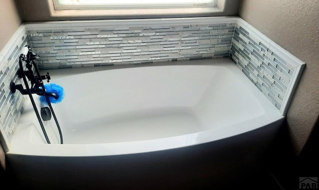 room details featuring a bathing tub and a textured wall