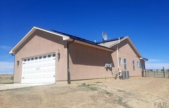 view of side of home with fence, stucco siding, and an attached garage
