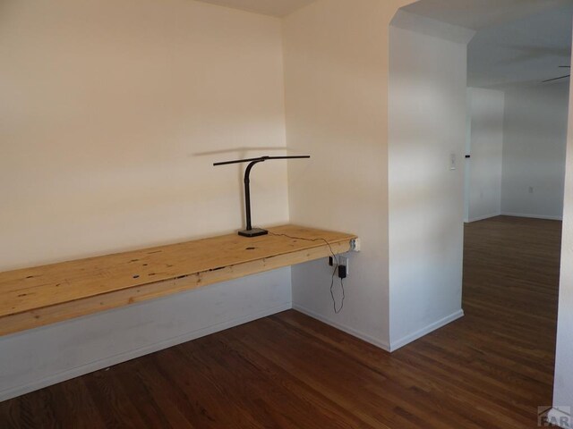 hallway featuring dark wood-style floors and baseboards