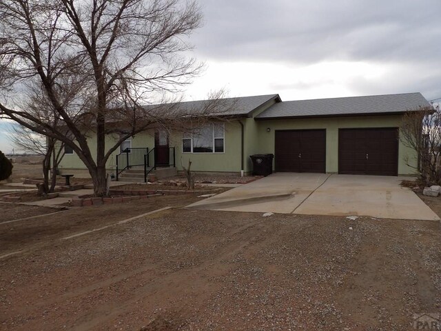 ranch-style house featuring a shingled roof, driveway, an attached garage, and stucco siding