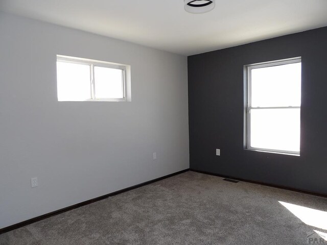 empty room with carpet flooring, visible vents, and baseboards