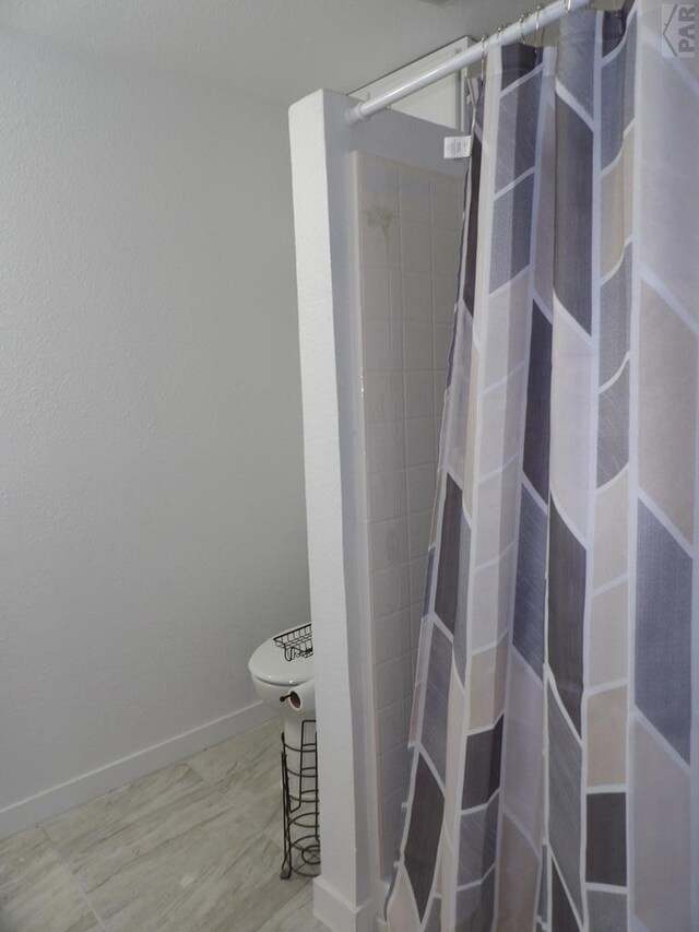 full bathroom with toilet, baseboards, and a shower with shower curtain