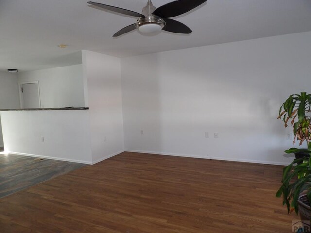 unfurnished room featuring ceiling fan, baseboards, and dark wood finished floors