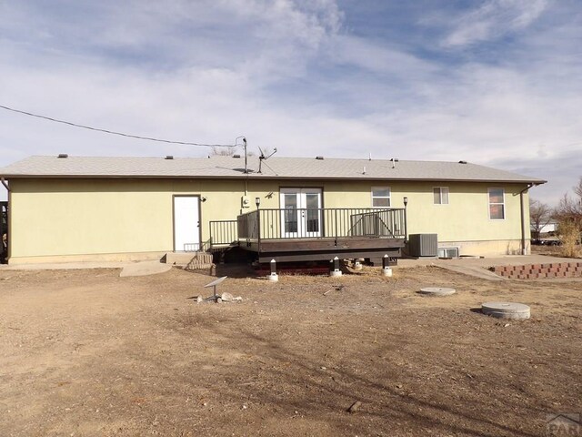 back of house featuring central air condition unit, a deck, and roof with shingles