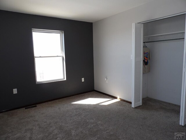 unfurnished bedroom with a closet, visible vents, and carpet flooring