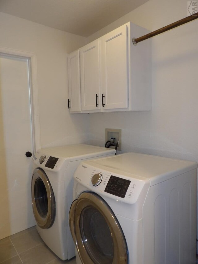 washroom featuring cabinet space, independent washer and dryer, and light tile patterned floors