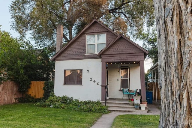 view of front of property with a front yard, fence, and stucco siding