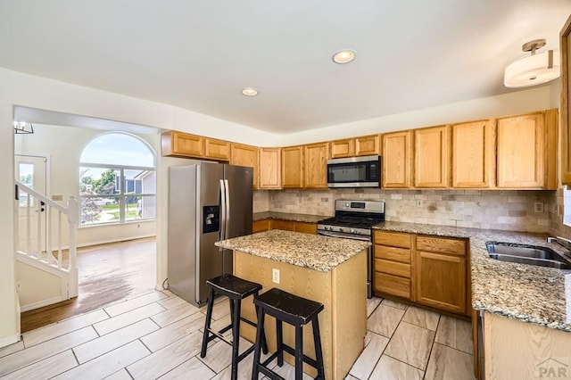 4366 Witches Hollow Ln, Colorado Springs, CO 80911 - kitchen featuring appliances with stainless steel finishes, a kitchen island, decorative backsplash, light stone countertops, and recessed lighting
