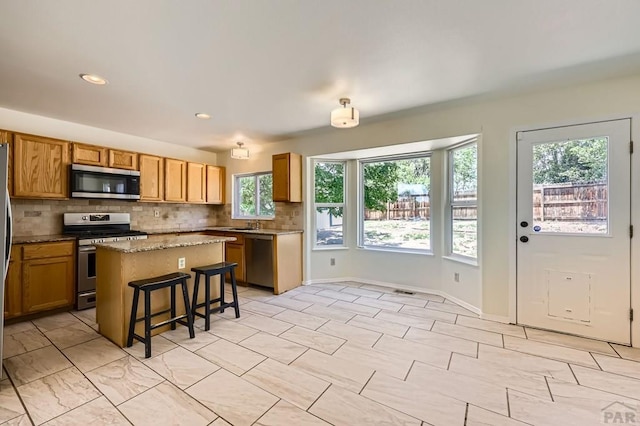 4366 Witches Hollow Ln, Colorado Springs, CO 80911 - kitchen with appliances with stainless steel finishes, tasteful backsplash, a center island, a kitchen breakfast bar, and recessed lighting
