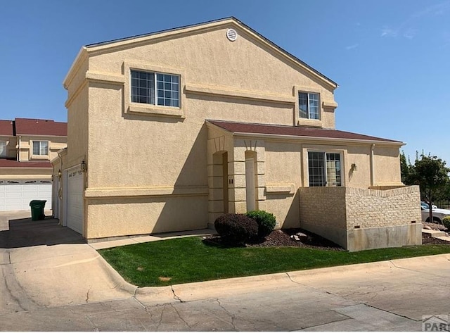 view of front of property featuring concrete driveway, an attached garage, and stucco siding