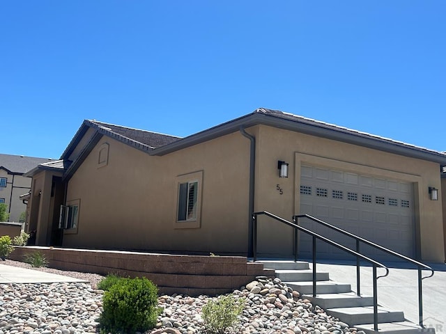 view of side of home with driveway, an attached garage, and stucco siding