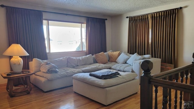 living room with a textured ceiling, wood finished floors, and stairs