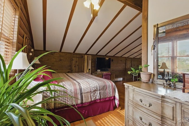 bedroom with wooden walls, a baseboard heating unit, wood finished floors, and lofted ceiling