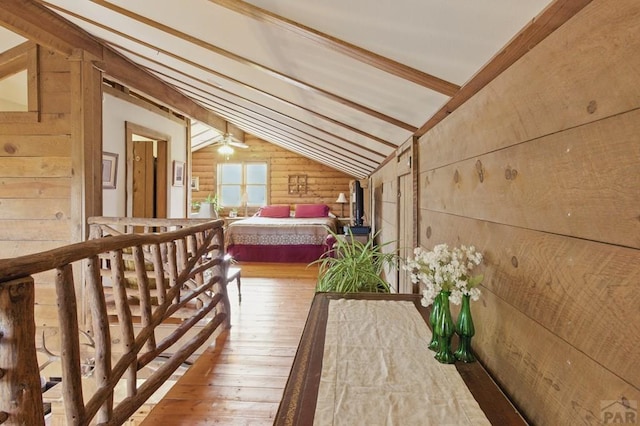 interior space with wood walls, vaulted ceiling with beams, and hardwood / wood-style floors