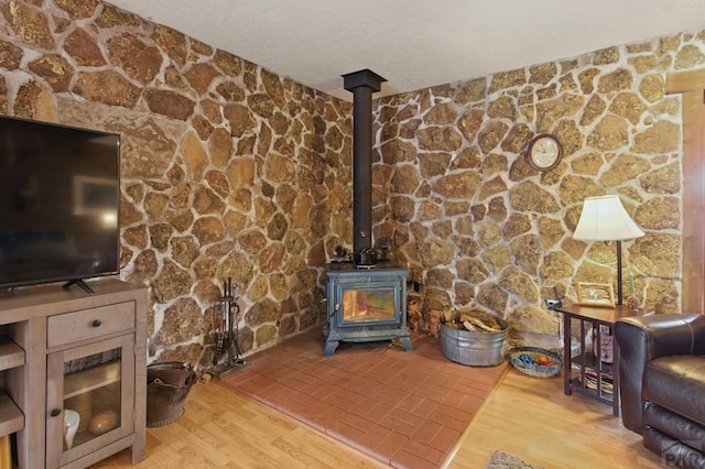 interior details featuring a textured ceiling, wood finished floors, and a wood stove