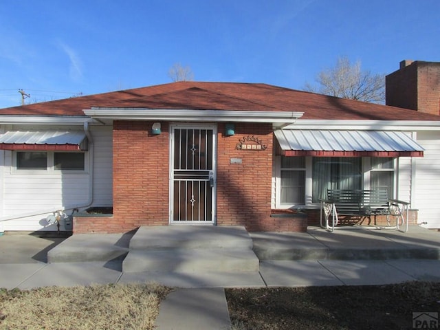 view of front of property featuring a chimney and brick siding