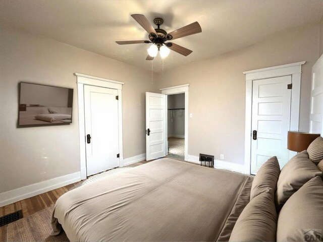 bedroom featuring baseboards, visible vents, ceiling fan, and wood finished floors