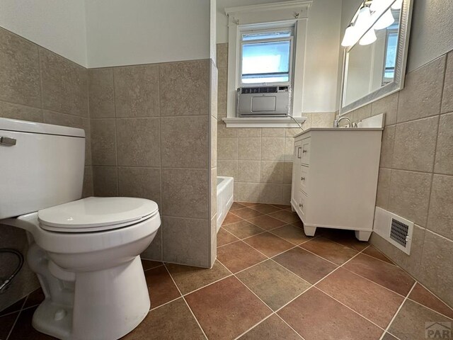 full bathroom with visible vents, toilet, tile patterned floors, a washtub, and tile walls