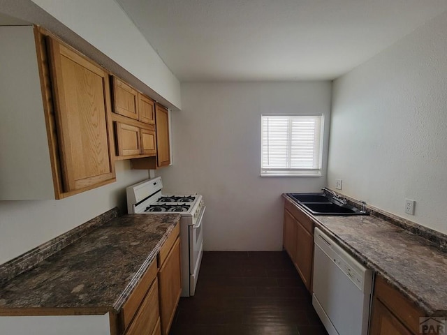 kitchen with white appliances, dark stone counters, brown cabinetry, dark wood-type flooring, and a sink