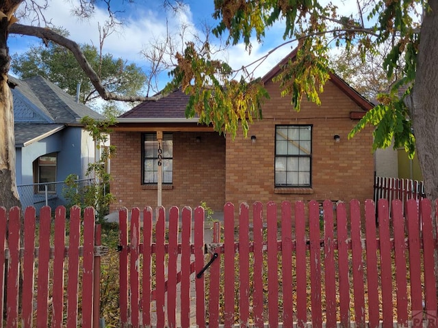 bungalow with a fenced front yard, a gate, and brick siding