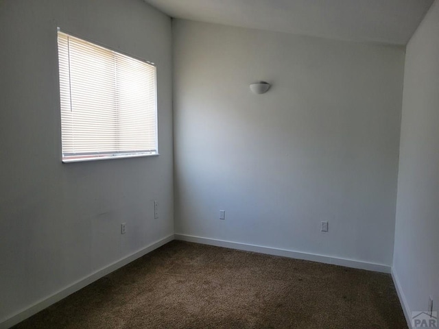 empty room with dark carpet and baseboards