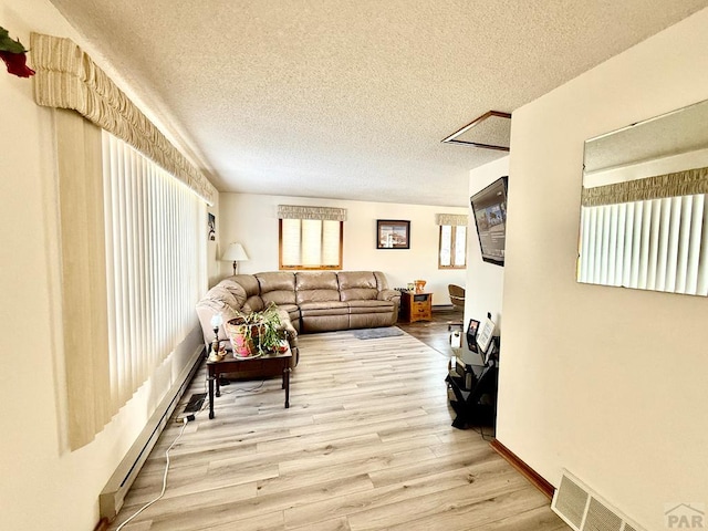 living room featuring light wood-style floors, visible vents, baseboard heating, and a textured ceiling