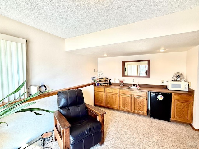 living area featuring wet bar, a textured ceiling, and light colored carpet