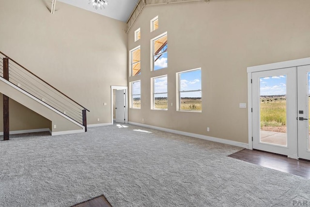 332 Yellow Bird Rd, Rye, CO 81069 - unfurnished living room featuring carpet floors, a towering ceiling, plenty of natural light, and stairway
