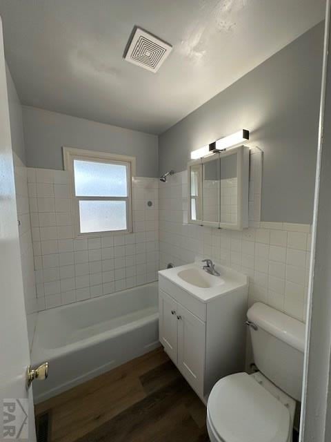 full bathroom featuring tile walls, shower / tub combination, toilet, visible vents, and wood finished floors