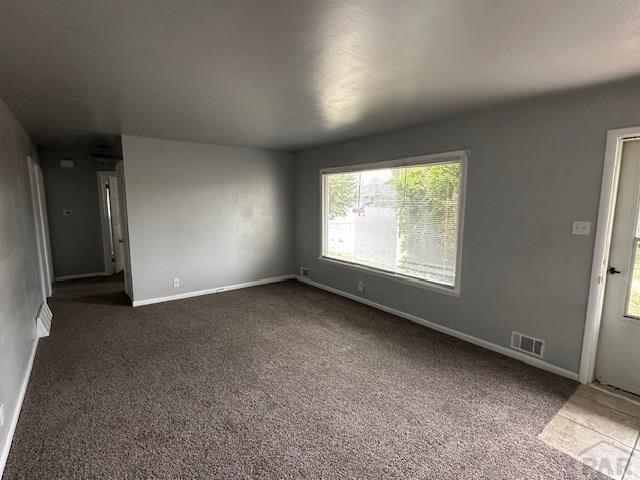 interior space featuring visible vents, dark colored carpet, and baseboards