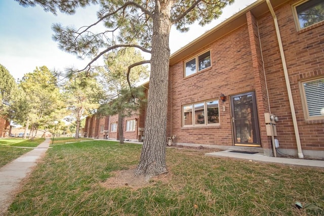 back of property featuring brick siding and a lawn