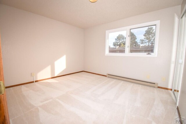 empty room with baseboards, a baseboard heating unit, and carpet flooring