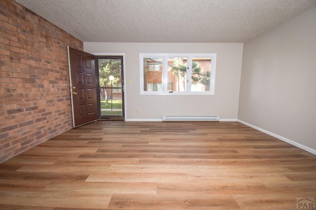 unfurnished room featuring brick wall, a baseboard radiator, light wood finished floors, baseboards, and a textured ceiling