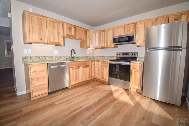 kitchen featuring light brown cabinetry, stainless steel appliances, and light wood-style floors