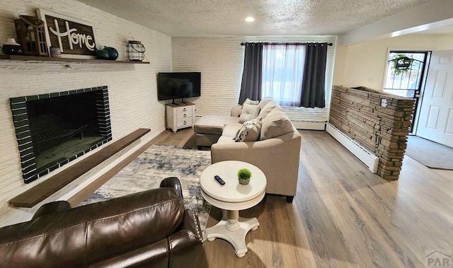 living area featuring a textured ceiling, a baseboard radiator, a fireplace, and wood finished floors