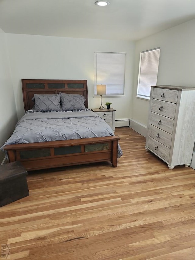 bedroom featuring light wood finished floors and a baseboard radiator