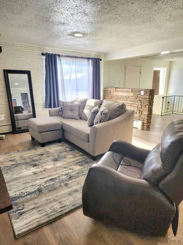 living area with a textured ceiling, a baseboard heating unit, and wood finished floors