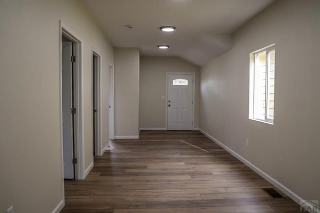 interior space featuring lofted ceiling, baseboards, visible vents, and wood finished floors