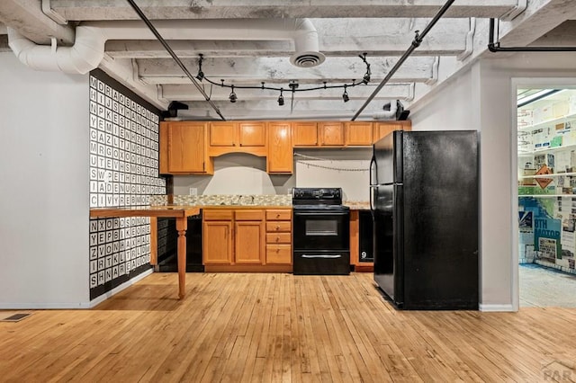 201 Lamkin St Unit 207, Pueblo, CO 81003 - kitchen featuring black appliances, light wood-type flooring, light countertops, and under cabinet range hood