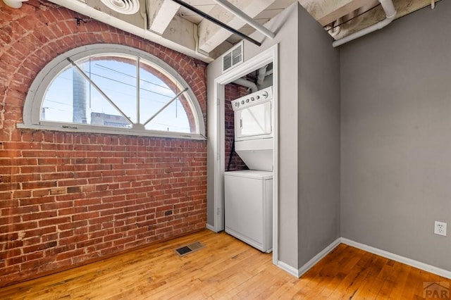 201 Lamkin St Unit 207, Pueblo, CO 81003 - washroom featuring stacked washer / dryer, brick wall, and light wood-style floors