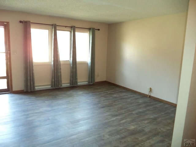 spare room featuring baseboards, a textured ceiling, and dark wood finished floors
