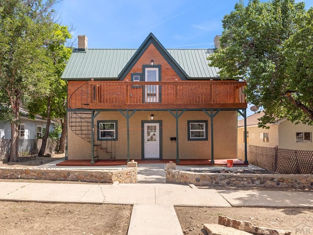 906 E 6th St, Pueblo, CO 81001 - view of front of property featuring a porch, a balcony, a chimney, a metal roof, and brick siding