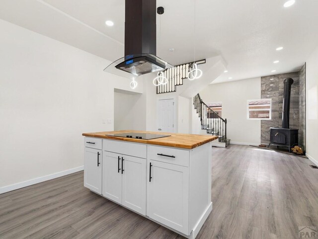 906 E 6th St, Pueblo, CO 81001 - kitchen with wood counters, black electric cooktop, island exhaust hood, light wood-style floors, and white cabinets